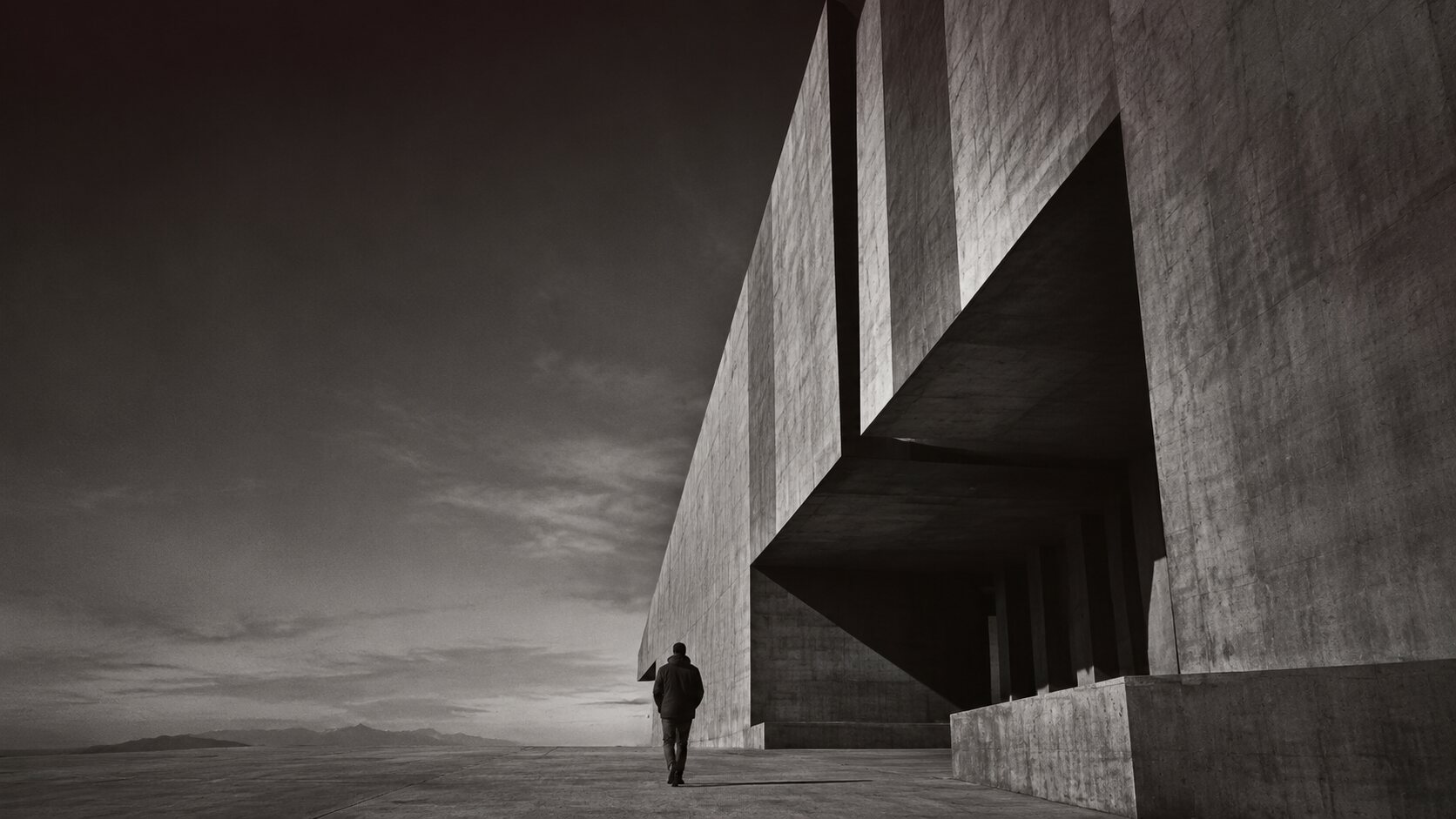Arquitectura brutalista en blanco y negro con una figura humana como escala.